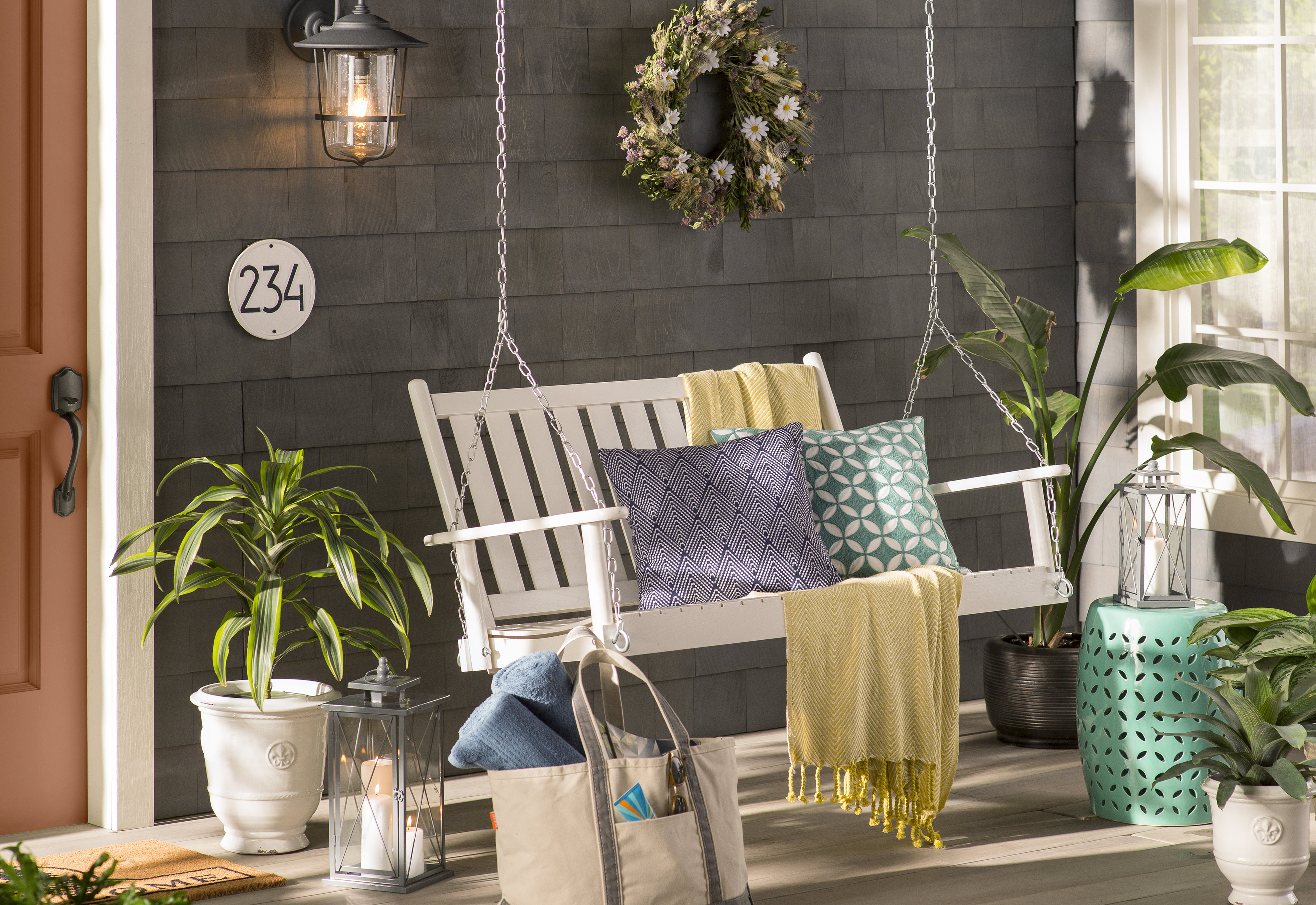 classic white porch swing with throw pillows and blankets