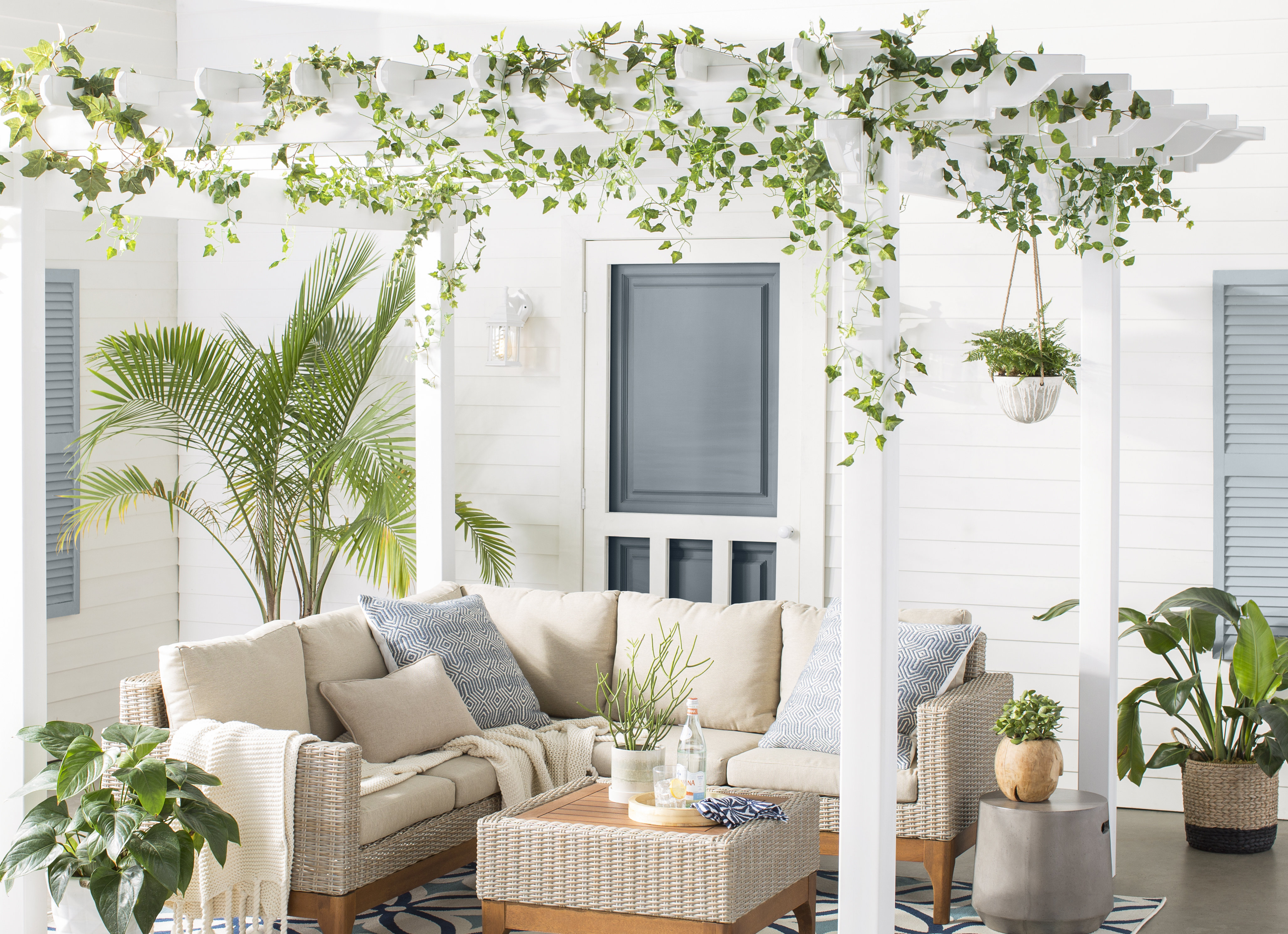 Clean white patio shaded by a pergola decorated with vines
